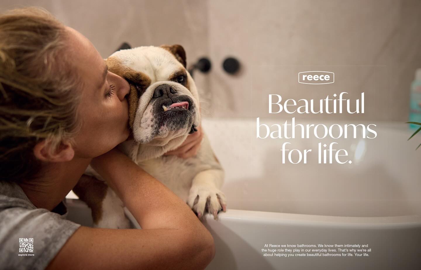 A woman kisses an English bulldog in a bathroom setting, next to the Reece brand advertisement featuring the tagline, “Beautiful bathrooms for life.”