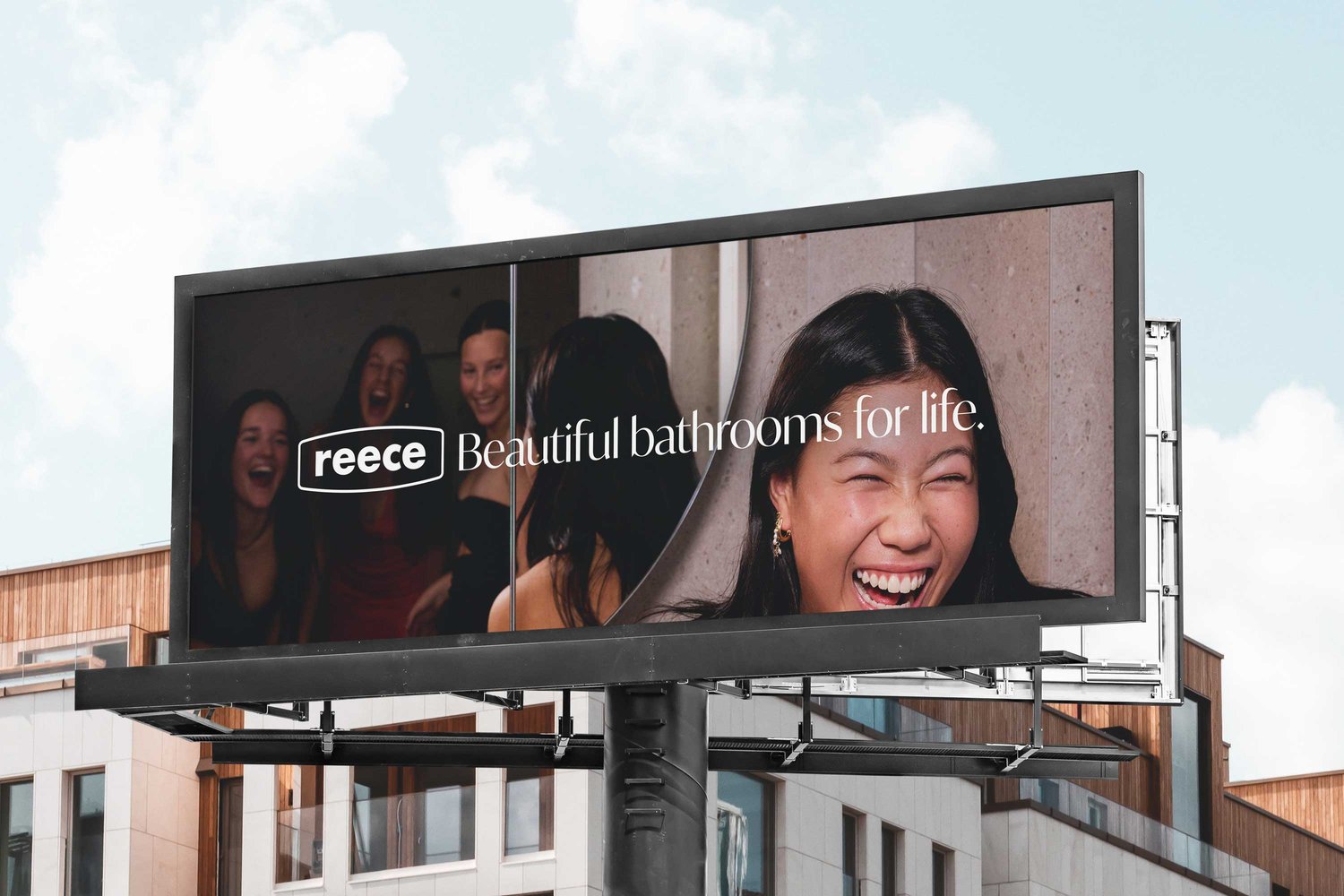 Billboard advertisement featuring joyful women and promoting beautiful bathrooms for life, set against a backdrop of a building and sky.