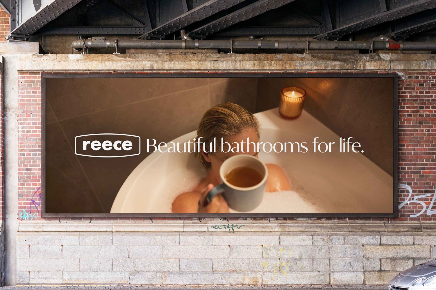Billboard advertising Reece bathrooms showing a person in a white bathtub holding a mug with a candle nearby
