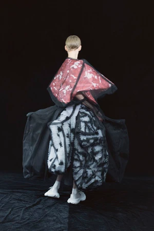 Model seen from behind wearing structured patterned garments against a dark backdrop for SSAW Magazine