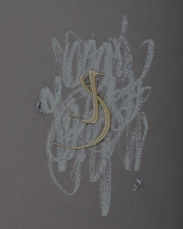 Sculptural curved gold jewelry piece positioned over expressive white chalk scribbles on a dark textured background.