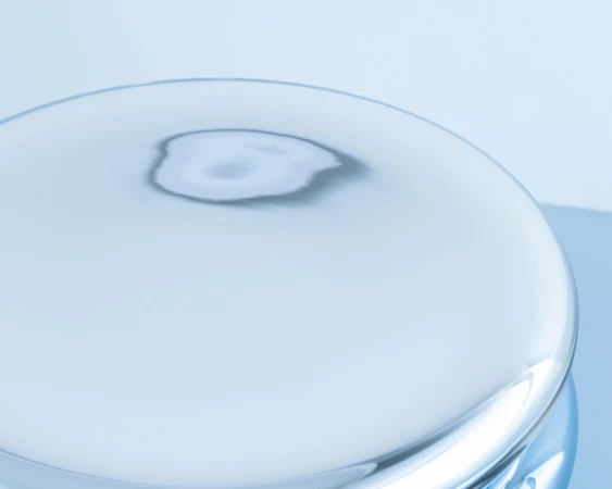 Abstract studio shot of a clear, rounded glass platform with a reflective surface, set against a soft, gradient blue background.