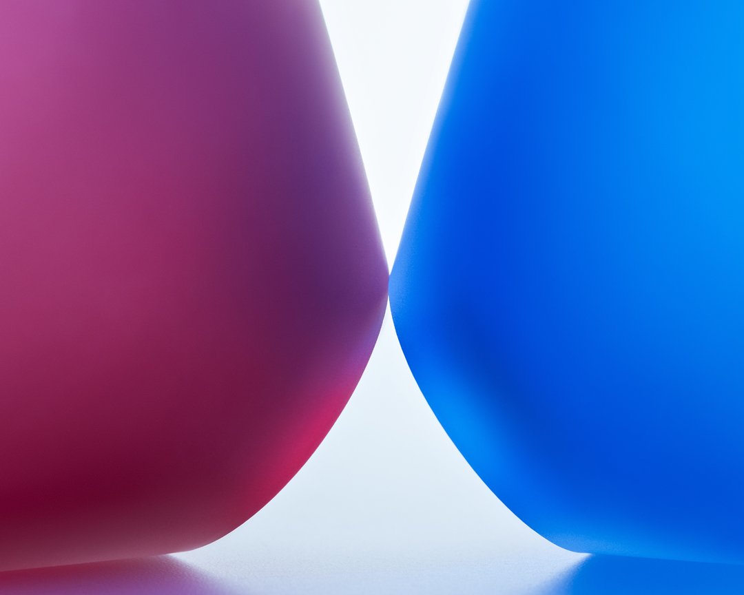 Abstract studio shot of two translucent forms, one cerise and one blue, curving toward one another in a colorful composition.