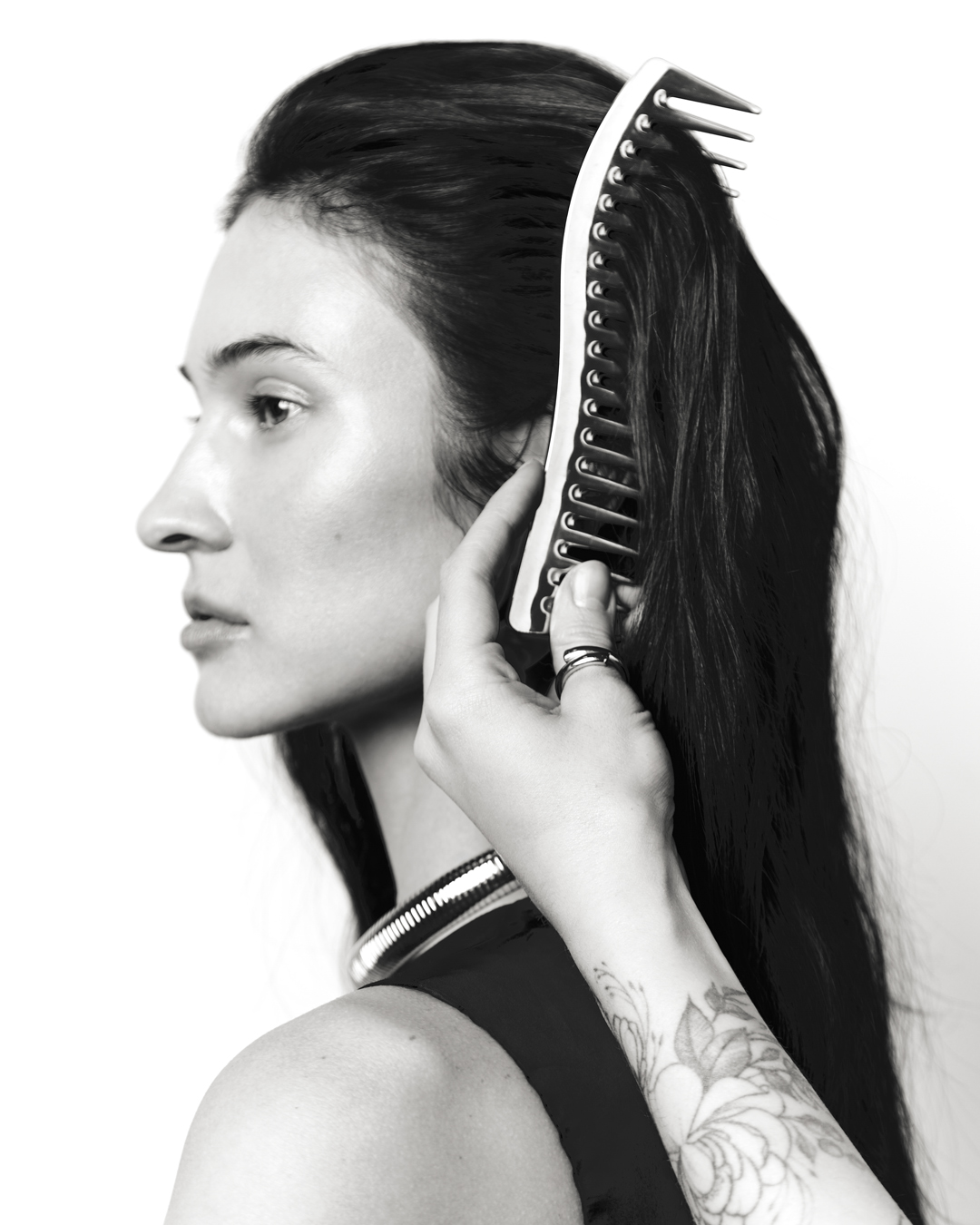 Monochrome portrait of a woman in profile with a comb in her hair, showcasing beauty and personal grooming against a clean white backdrop.