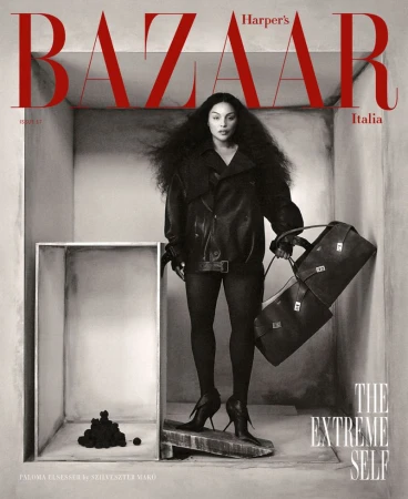 Fashion magazine cover featuring a woman with voluminous hair wearing a black leather jacket, holding a handbag, in a geometric setting.