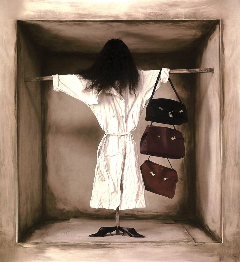 Conceptual studio shot features a mannequin in a white coat with a black wig, displayed in a box-like room with three handbags.
