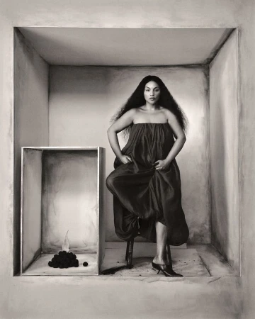 Elegant adult female posing on a stool inside a painted box, wearing a strapless dress and heels, next to a pile of objects.  