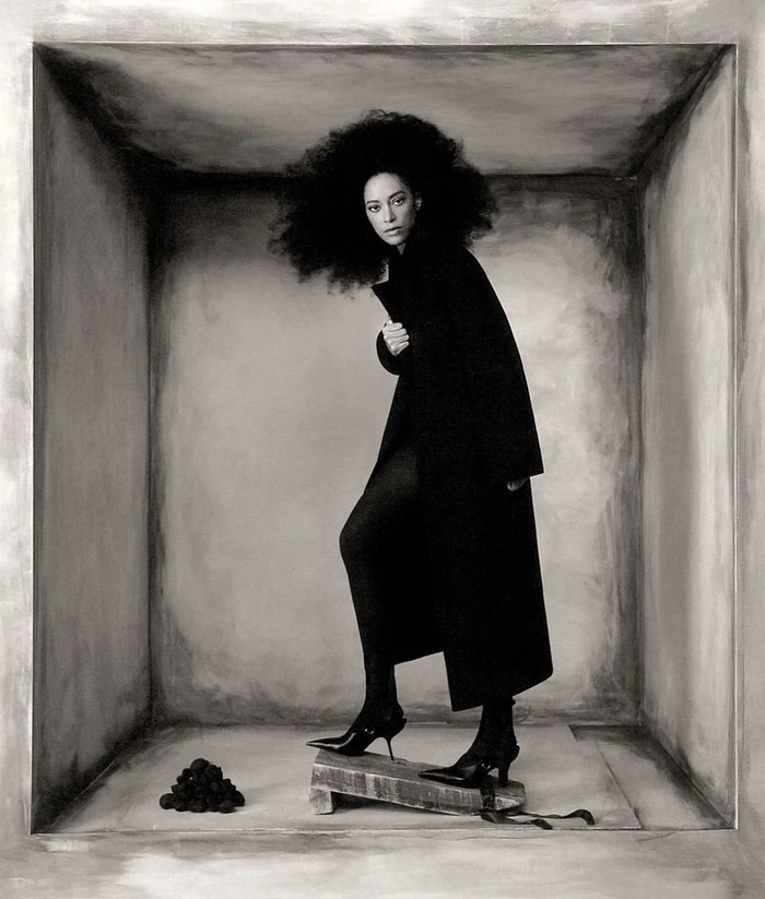 Paloma Elsesser in a black coat posing inside a box-like set for Harper's Bazaar Italia