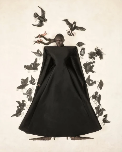 An African woman wearing a long black dress surrounded by black-and-white bird illustrations creates a surreal fashion portrait.