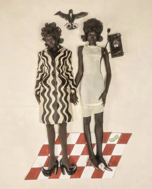 Two women in vintage-inspired fashion pose with a bird figure and purse, standing on a red and white checkered surface against a white backdrop.