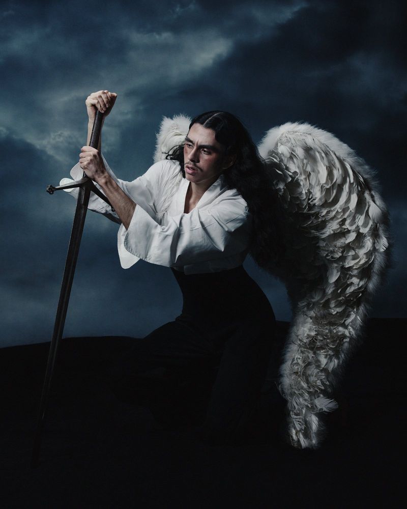 Dramatic portrait of a winged man with a sword against a stormy sky, conveying a sense of struggle and resilience in a dark fantasy setting.