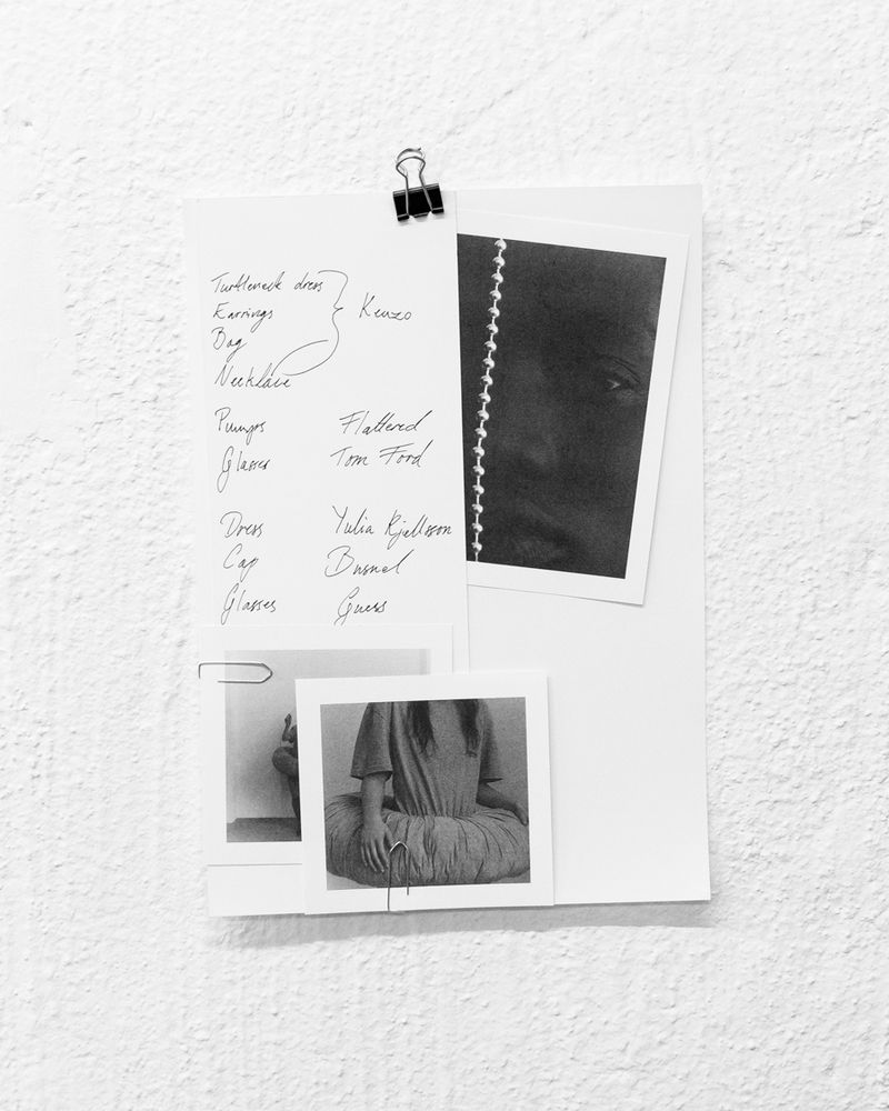 Black and white wall-mounted display with handwritten fashion notes and three attached photographs, capturing a minimalist aesthetic.