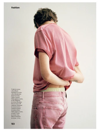Fashion editorial shot of a person in pink shirt and pants, back turned, showing the waistline in a brightly lit indoor setting.