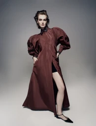 Model in a burgundy dress with dramatic puffy sleeves posing against a grey studio backdrop for Harper's Bazaar Australia.
