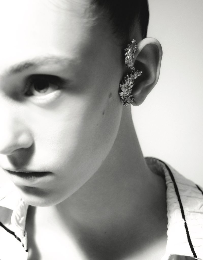 Close-up shot of a person wearing decorative ear cuffs, set against a bright white background, showcasing fashion and beauty.