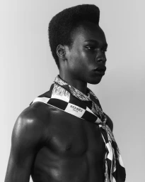 Black and white profile portrait of a man wearing a patterned neck scarf against a plain background.