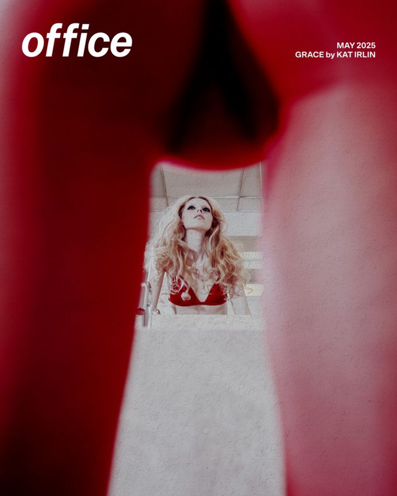Fashion magazine cover featuring a blond woman in a red bikini top, viewed through a blurred, red-toned foreground frame.