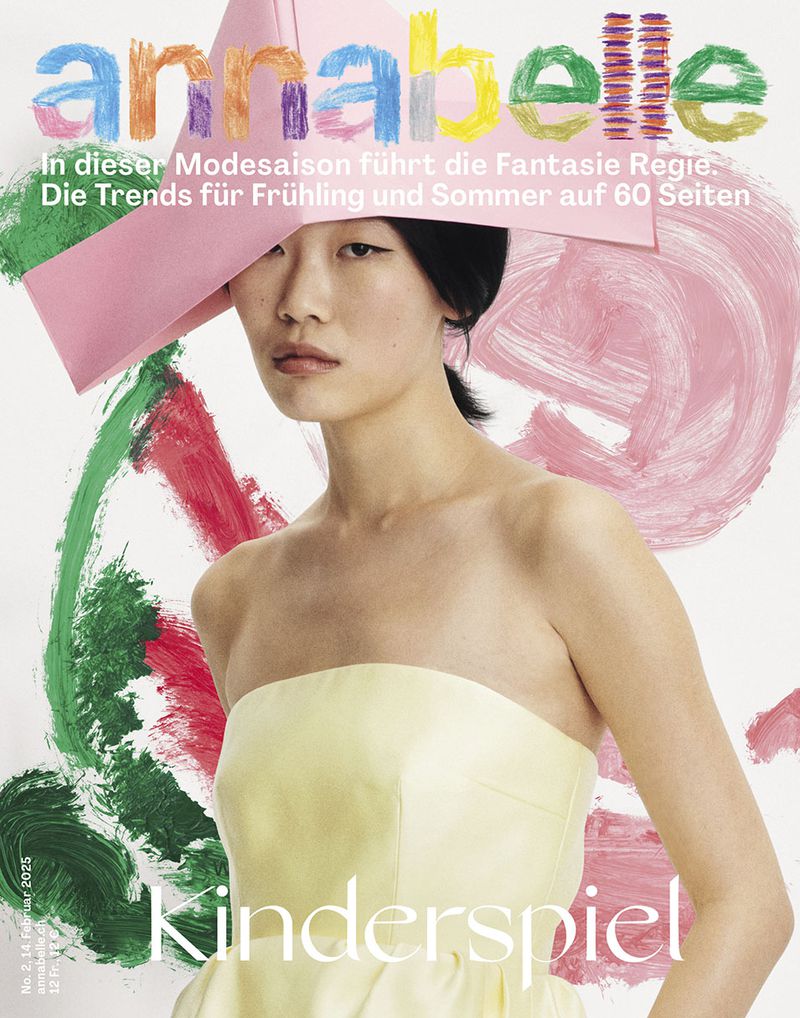 Magazine cover featuring an Asian woman with pale yellow strapless top and pink hat, posing against a colorful painted background.