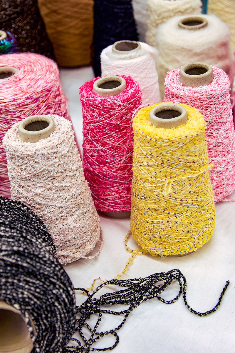 Colorful collection of yarn spools in yellow, pink, white, and black, creating a textured and vibrant display on a white surface.