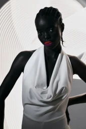 Black woman with bright red lipstick wearing a white halter top against an abstract patterned circular light backdrop
