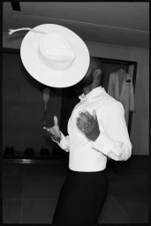 Monochrome portrait of Lakeith Stanfield wearing a white shirt and tossing a white hat in the air for Ferragamo.