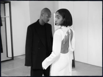 Monochrome fashion portrait featuring a woman in a white open-back dress and a man in a black blazer.