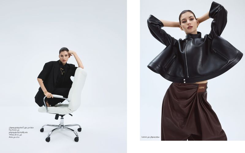 Fashion editorial shot of a woman in stylish black and brown outfits, sitting on a chair in a studio against a bright white background.
