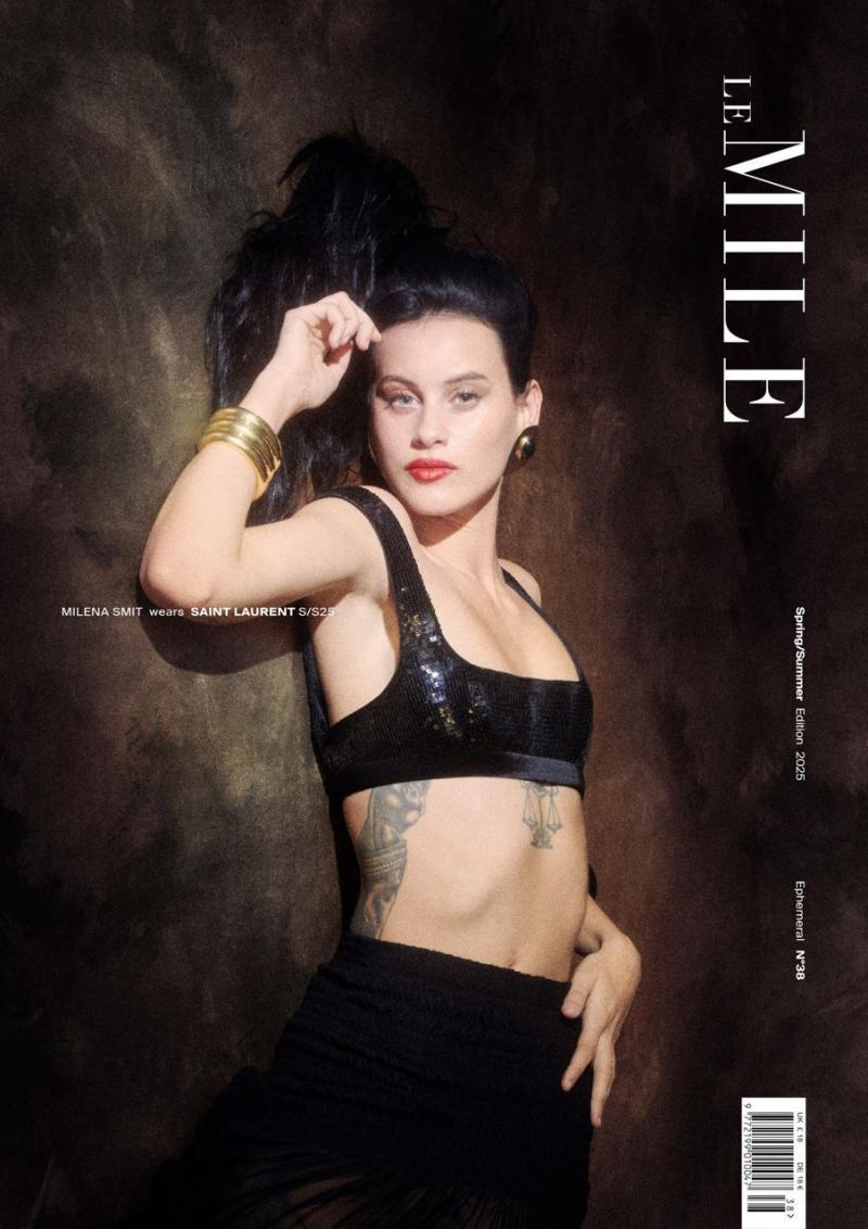 A fashion magazine cover featuring a model with dark hair, red lipstick, and gold bracelets, wearing a black top and skirt.