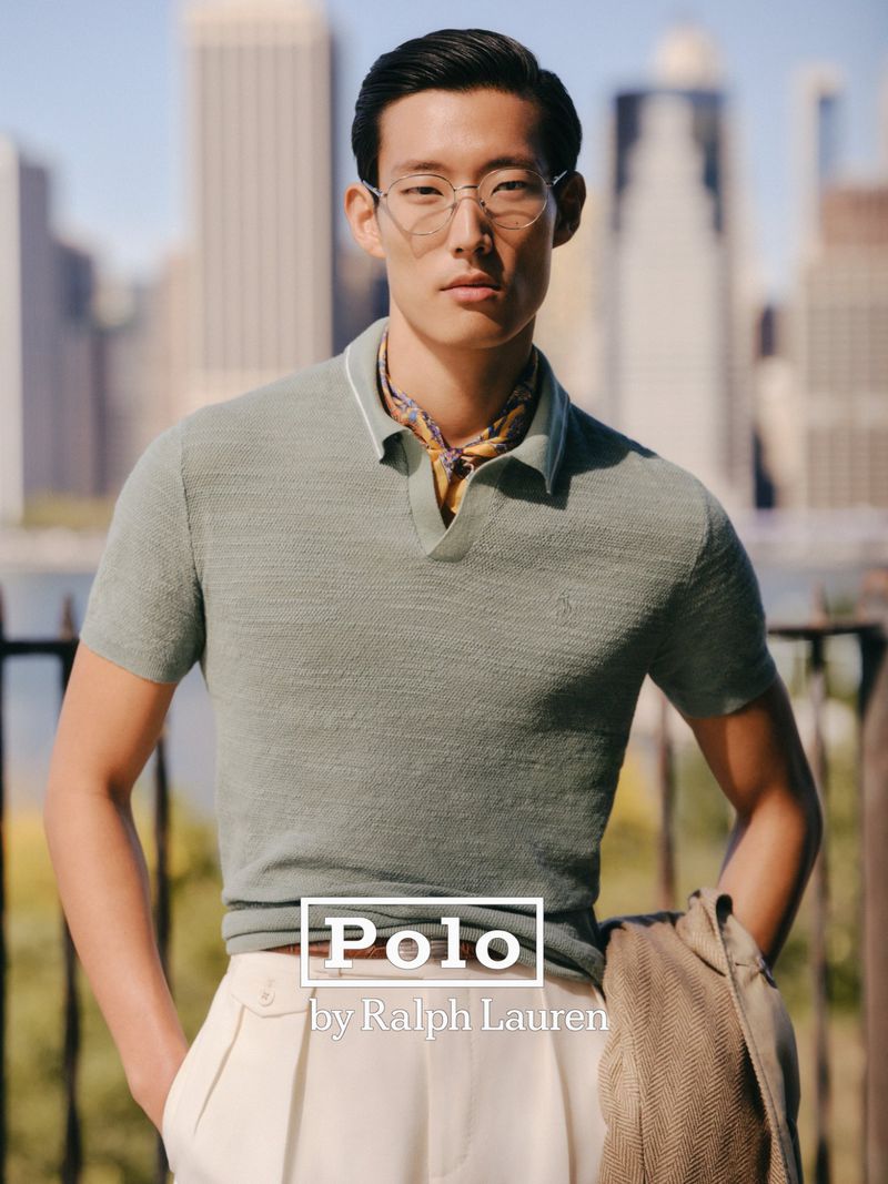 A stylish Asian male model showcases Polo Ralph Lauren against a backdrop of a city skyline and water during daylight hours.