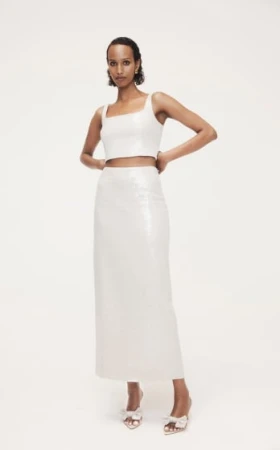 Model in white crop top and matching long skirt posing against a seamless white background for Witchery