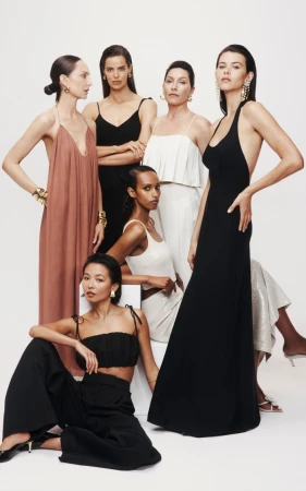 Group of six women in fashionable clothing, posing against a white backdrop, displaying elegant dresses, tops and bottoms in a studio shot.