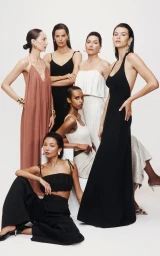 Group of female fashion models posing in elegant eveningwear against a clean white seamless studio background.