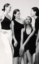 Four women smiling and interacting against a plain white studio background in a fashion campaign