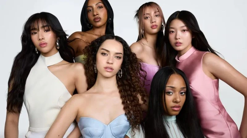 Diverse group of six young adult women posing in studio. Fashion shot showcasing varied hairstyles, makeup, and pastel color dresses.