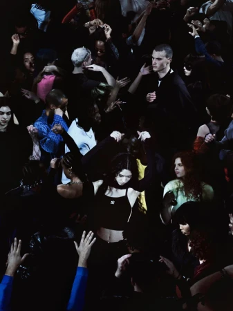 Diverse group of young adults dancing in a dark club setting. People are raising hands and moving to music, creating a vibrant atmosphere.