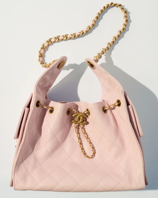 Luxury pink quilted Chanel shoulder bag featuring a gold chain strap and CC logo charm, displayed on a white background in a studio shot.