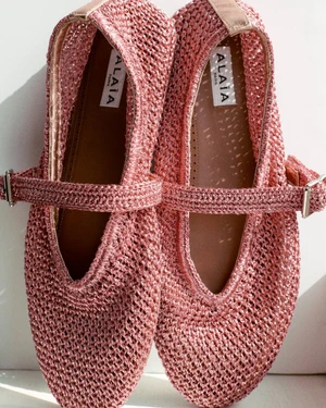 Pink mesh Mary Jane flats with buckled straps photographed from above on a clean white background