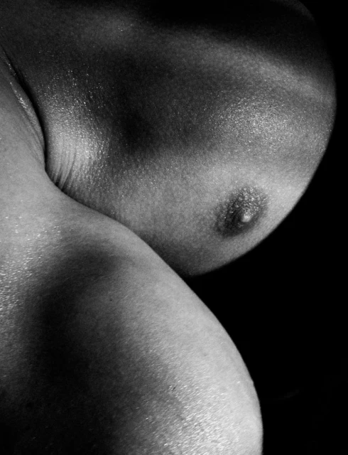 Close-up, monochromatic shot featuring the curves and contours of a person's upper body, creating a visually striking, intimate composition.