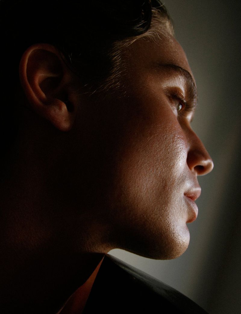 Portrait of a man in profile, featuring dramatic side lighting and dark shadows enhancing his features and contours.