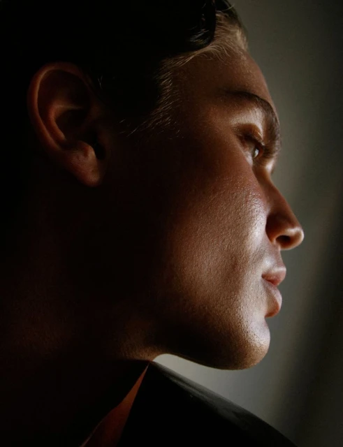 Portrait of a man in profile, featuring dramatic side lighting and dark shadows enhancing his features and contours.