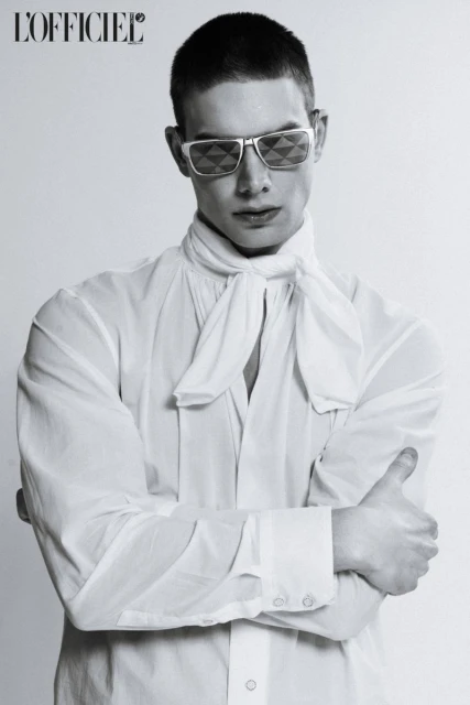 Black and white portrait of an adult man wearing sunglasses and a white shirt with a necktie, shot in a photo studio against a white background.