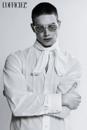 Black and white portrait of an adult man wearing sunglasses and a white shirt with a necktie, shot in a photo studio against a white background.