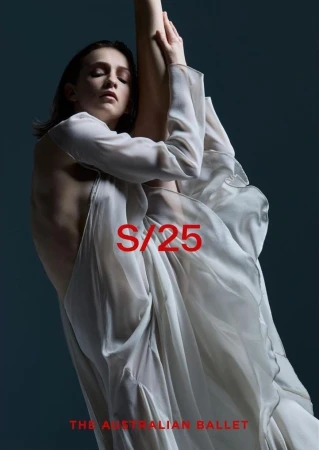 Female ballet dancer in flowing white dress poses gracefully in a studio against a dark background, showcasing a delicate and artistic movement.