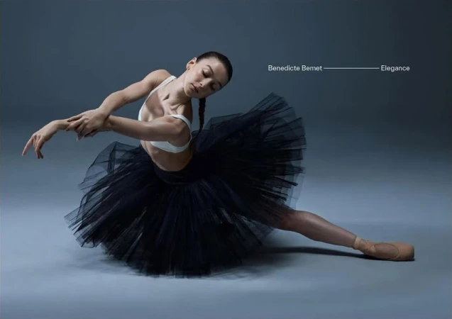 Ballet dancer in black tutu and white top, poised gracefully in studio. Professional dance photography, artistic movement, elegant aesthetic.