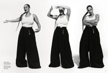 Black and white fashion editorial featuring Jorja Smith posing in a white tank top and wide-legged trousers against a seamless white background.