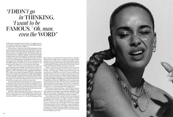 Black and white portrait of Jorja Smith with a long braided ponytail and layered silver chain necklaces against a white background