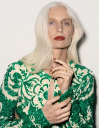 Model with long white hair wearing a green sequin dress posing against a plain white background for Harper's Bazaar France.