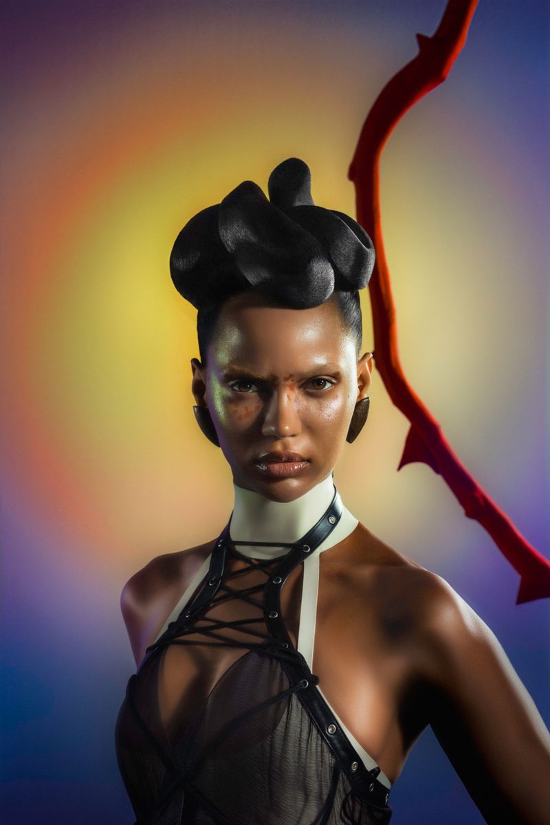 Striking beauty portrait of a woman with dramatic black headpiece, black bodice, white collar, and a red branch against a colorful background.