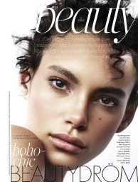 Close-up beauty portrait of a young female model with dark curly hair and natural makeup against a plain white background
