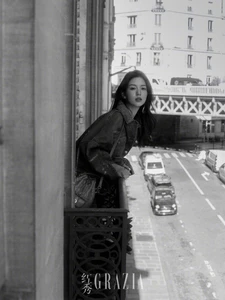 Woman leaning on a balcony railing overlooking a city street in a black and white editorial photograph for Grazia China